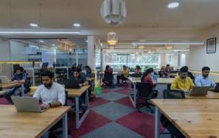 Professionals working in a modern coworking space near Silk Board with open desks, meeting rooms, and collaborative startup environment