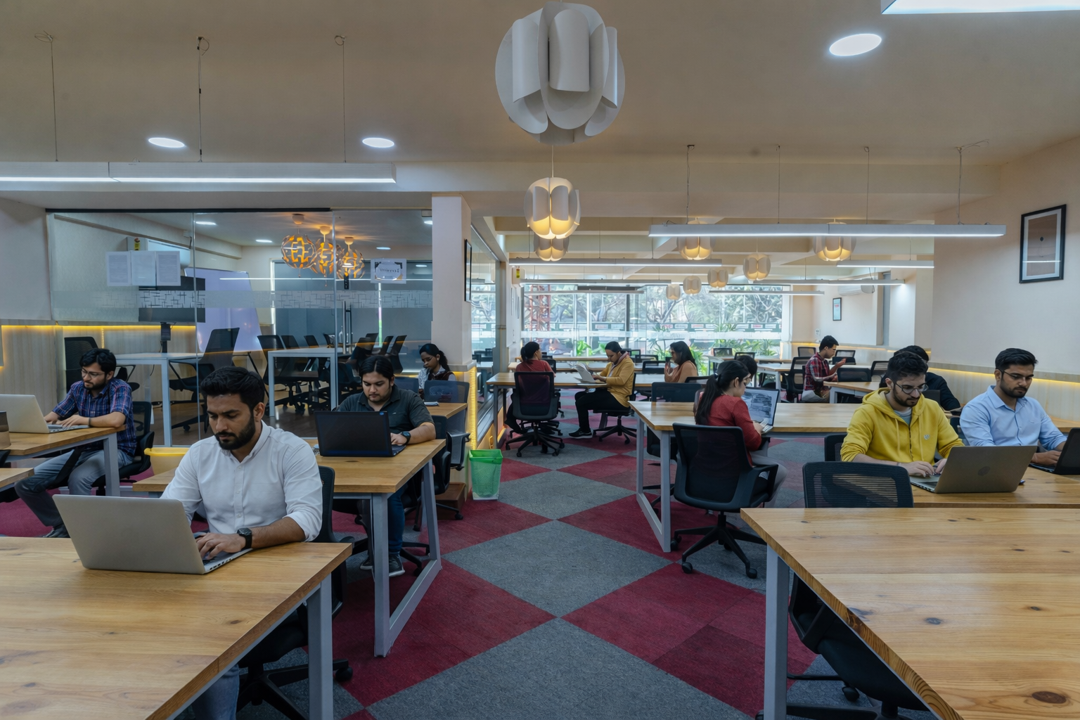 Professionals working in a modern coworking space near Silk Board with open desks, meeting rooms, and collaborative startup environment